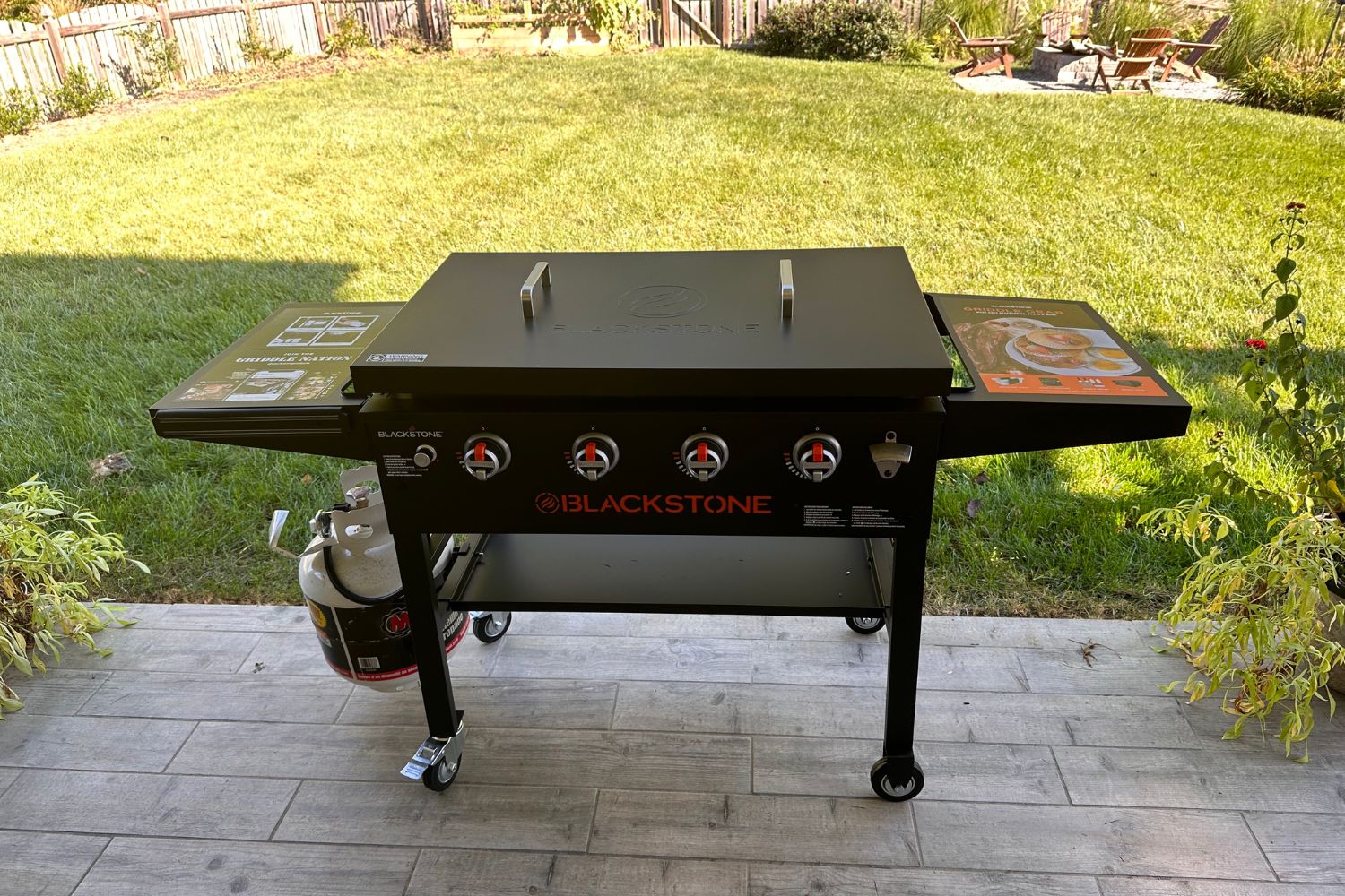 Blackstone 36-Inch Griddle with hard cover on stone patio in sunny backyard.