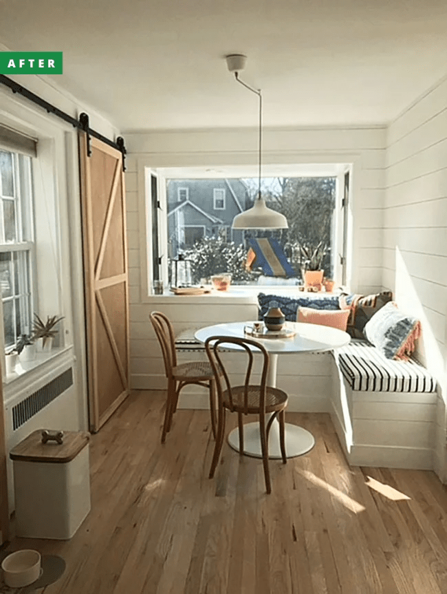 A breakfast nook after renovation with a banquette and barn door.