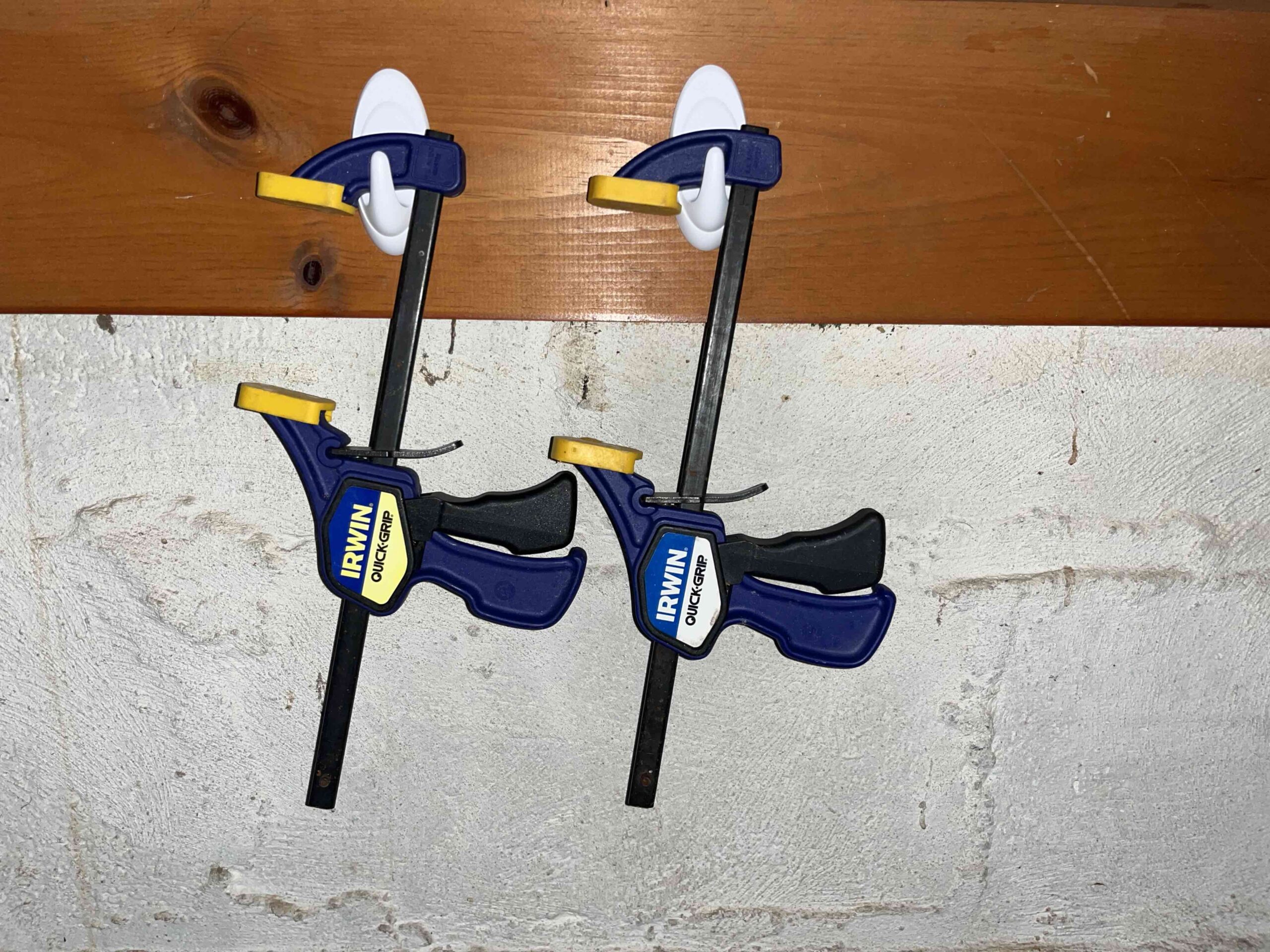 Two Quick Grip Tools Hanging from command Hooks in Garage