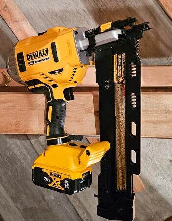 DeWalt Cordless Framing Nailer standing upright with attached nail cartridge in front of studs.