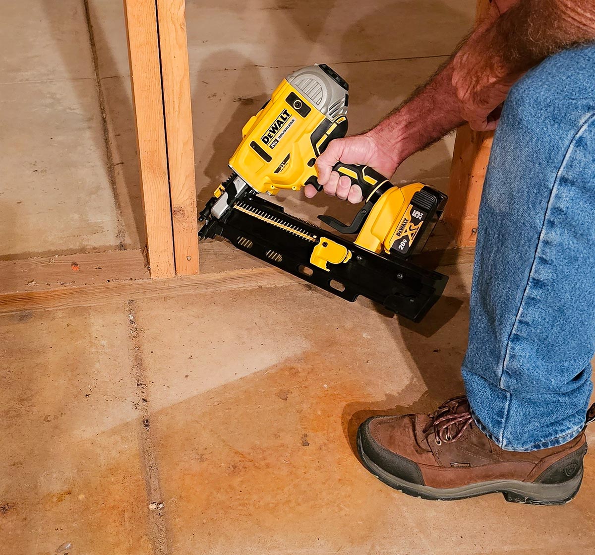 Building contractor using DeWalt Cordless Nailer to fasten stud to bottom plate.