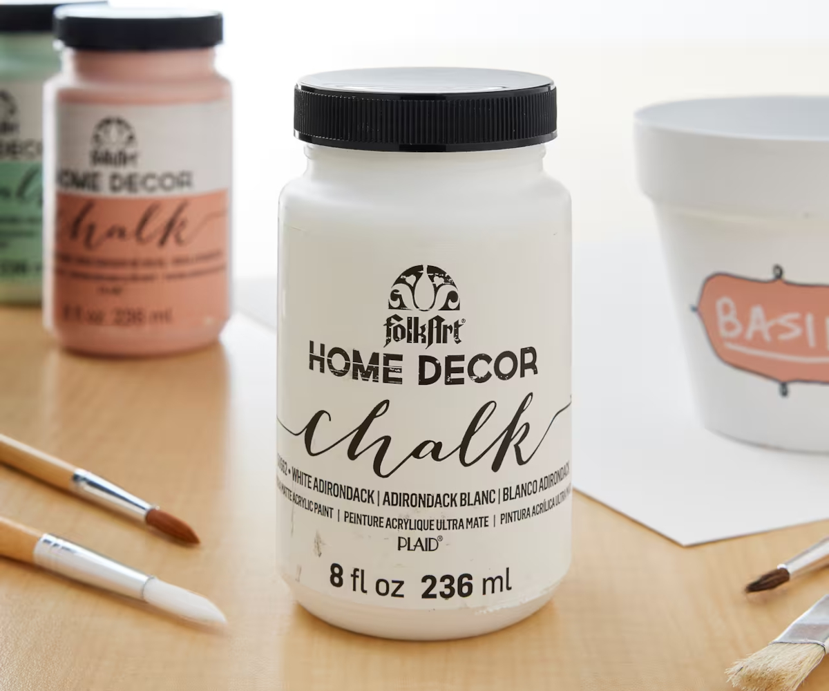 An 8-ounce jar of white FolkArt Home Decor chalk paint on a staged craft table.