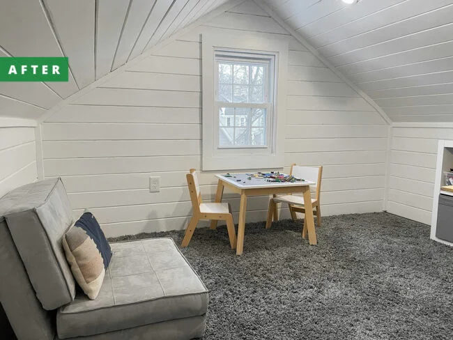 An attic has been turned into a white and grey playroom with child sized furnishings.