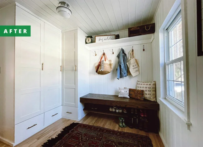A white mudroom with cabinet storage and hooks for coats.