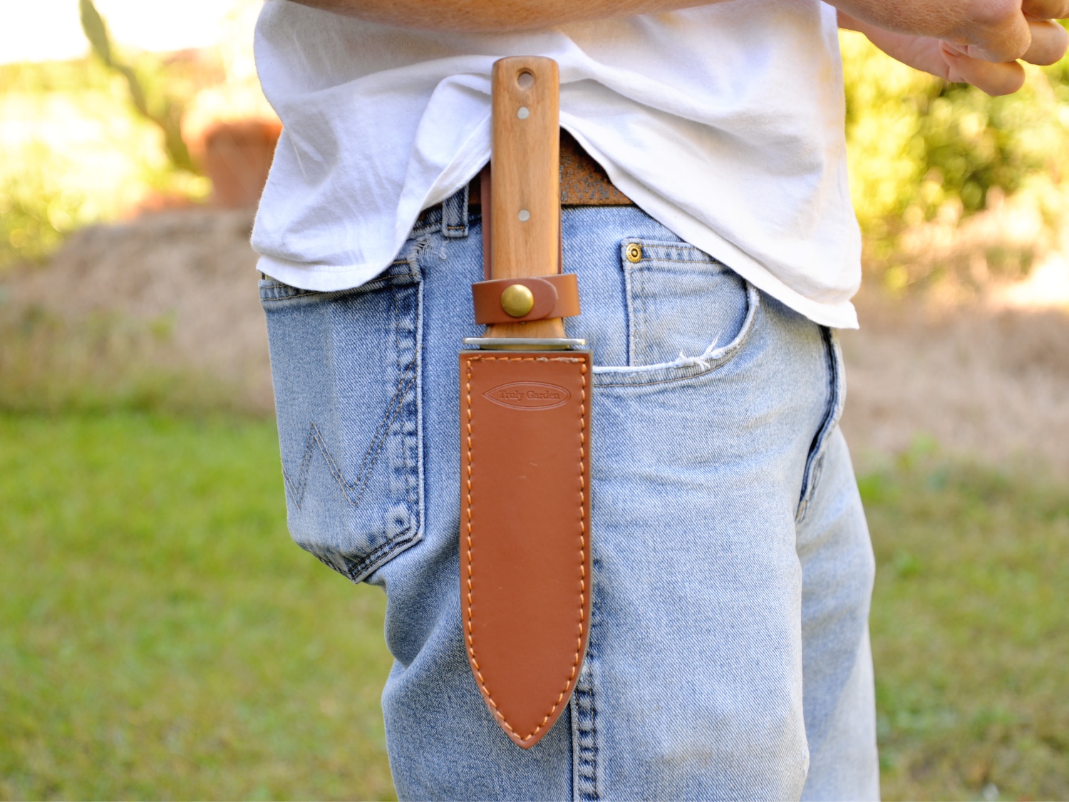 A person wearing the Truly Garden hori hori knife in its sheath on their hip.
