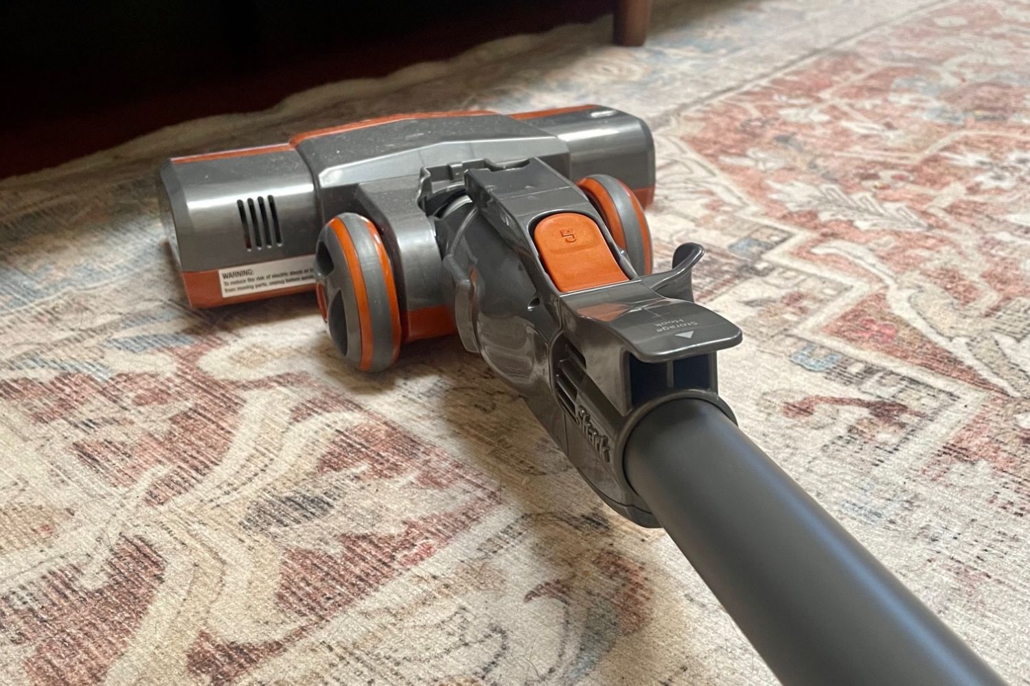 Shark Rocket vacuum cleaning cream and red area rug near couch.