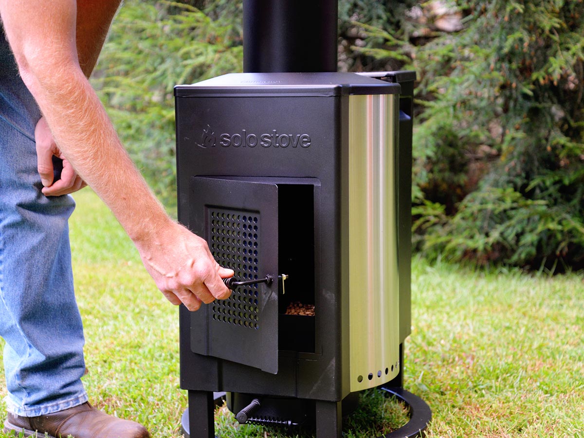 Person opening the door of the firebox on a Solo Stove tower patio heater.