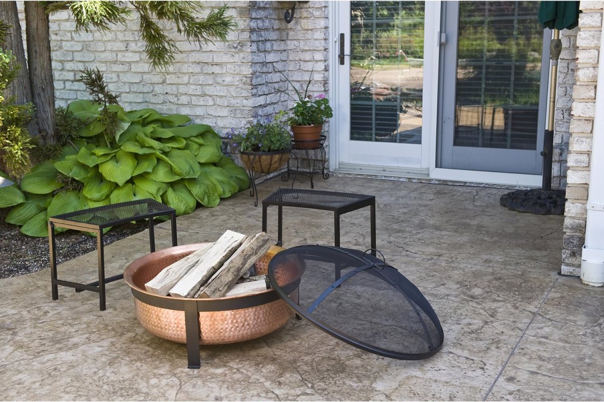The best copper fire pit option loaded with firewood and ready to start on a cement bricked patio