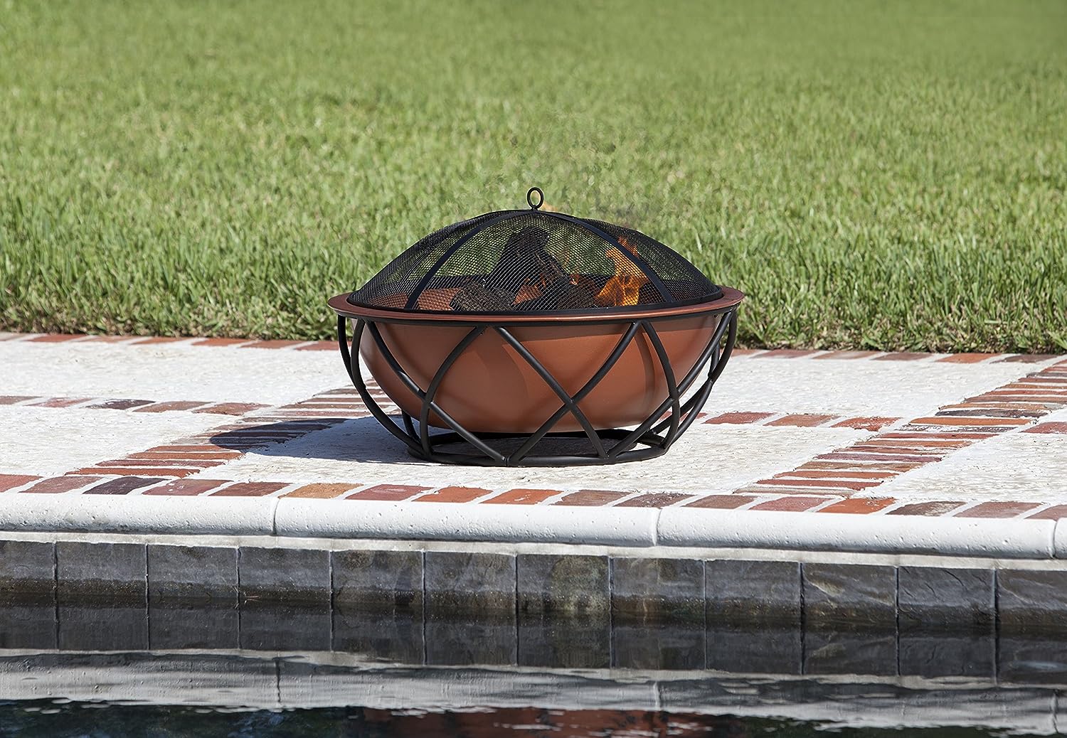 The best copper fire pits option with a fire burning in it near the edge of a swimming pool