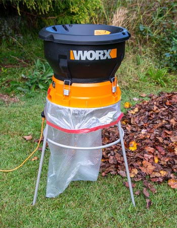Worx leaf mulcher set up with a bag next to a pile of leaves