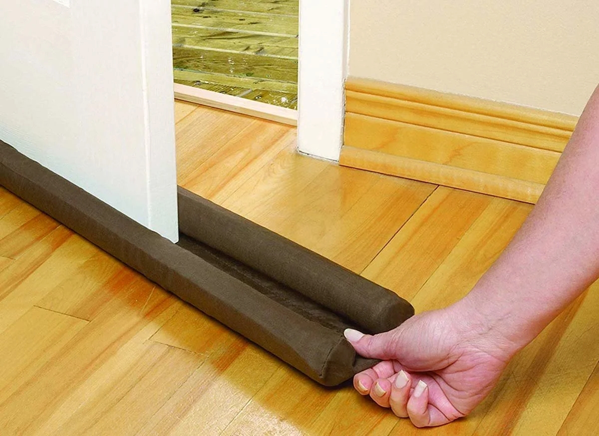 Hand sliding black foam insulation on bottom of door.