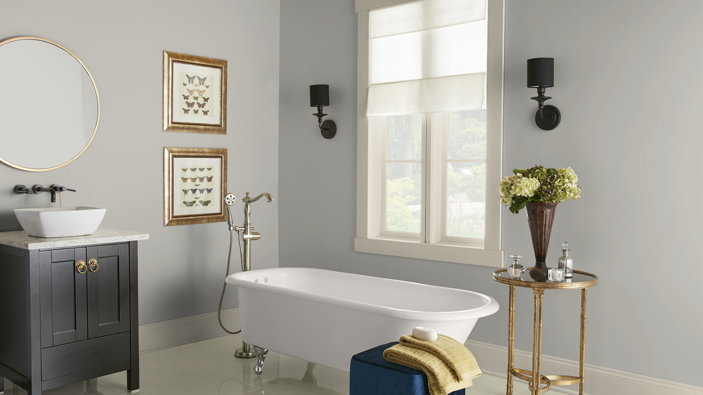 A vintage inspired clawfoot tub sits in an elegantly decorated bathroom with grey walls