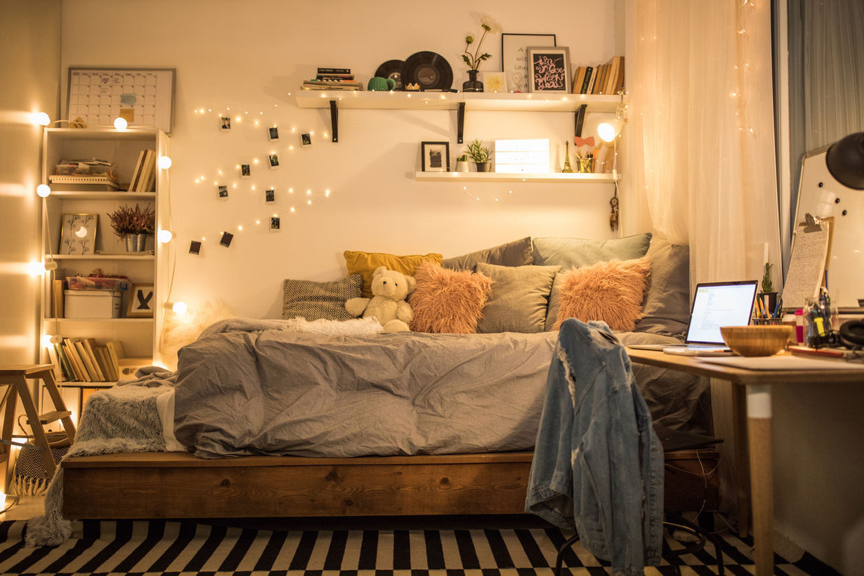 A-string-of-lights-that-holds-photos-is-hanging-on-a-wall-in-a-teen-bedroom-with-bed-and-desk-and-shelves.