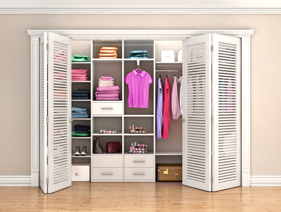 closet-with-white-bifold-louvered-doors-that-have-vent-slats-in-front-of-a-closet-with-bright-clothing