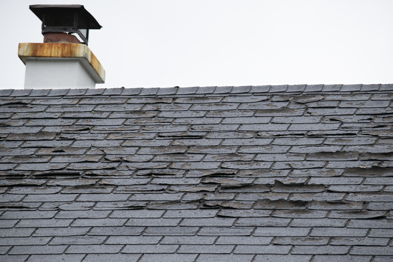 Damage to asphalt and asbestos shingles, gutter systems, chimney and roof flashing on residential home.