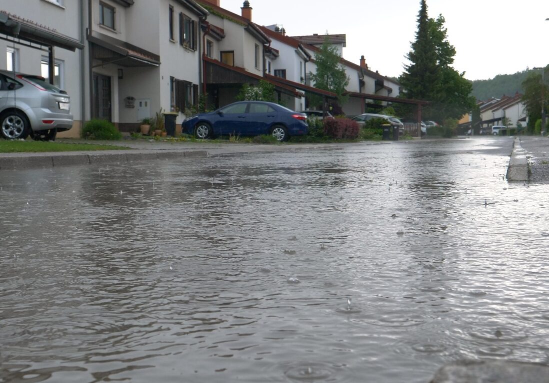 suburban street during rain storm with street filling with runoff from concrete driveways