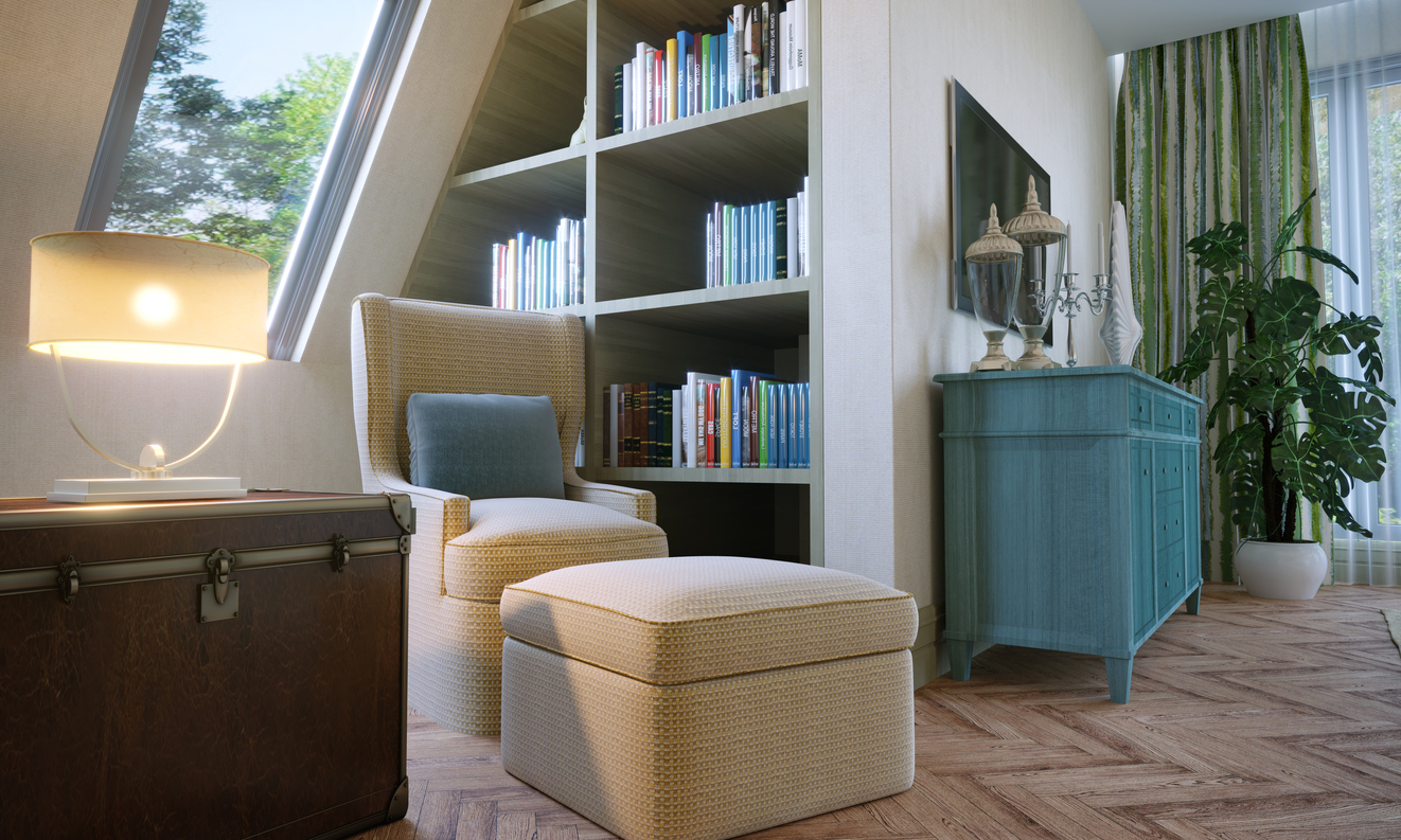 A reading area in attic bedroom, includes a chair, an inset bookcase and books.