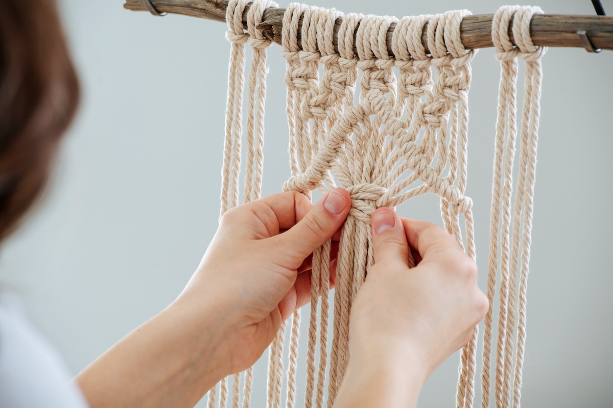 Woman learning how to macrame at home.