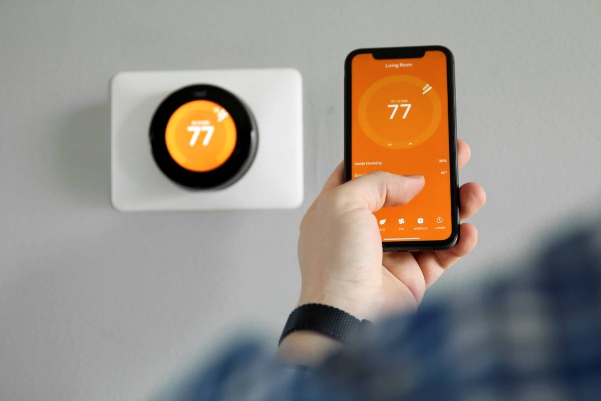 Person using smart thermostat via phone.