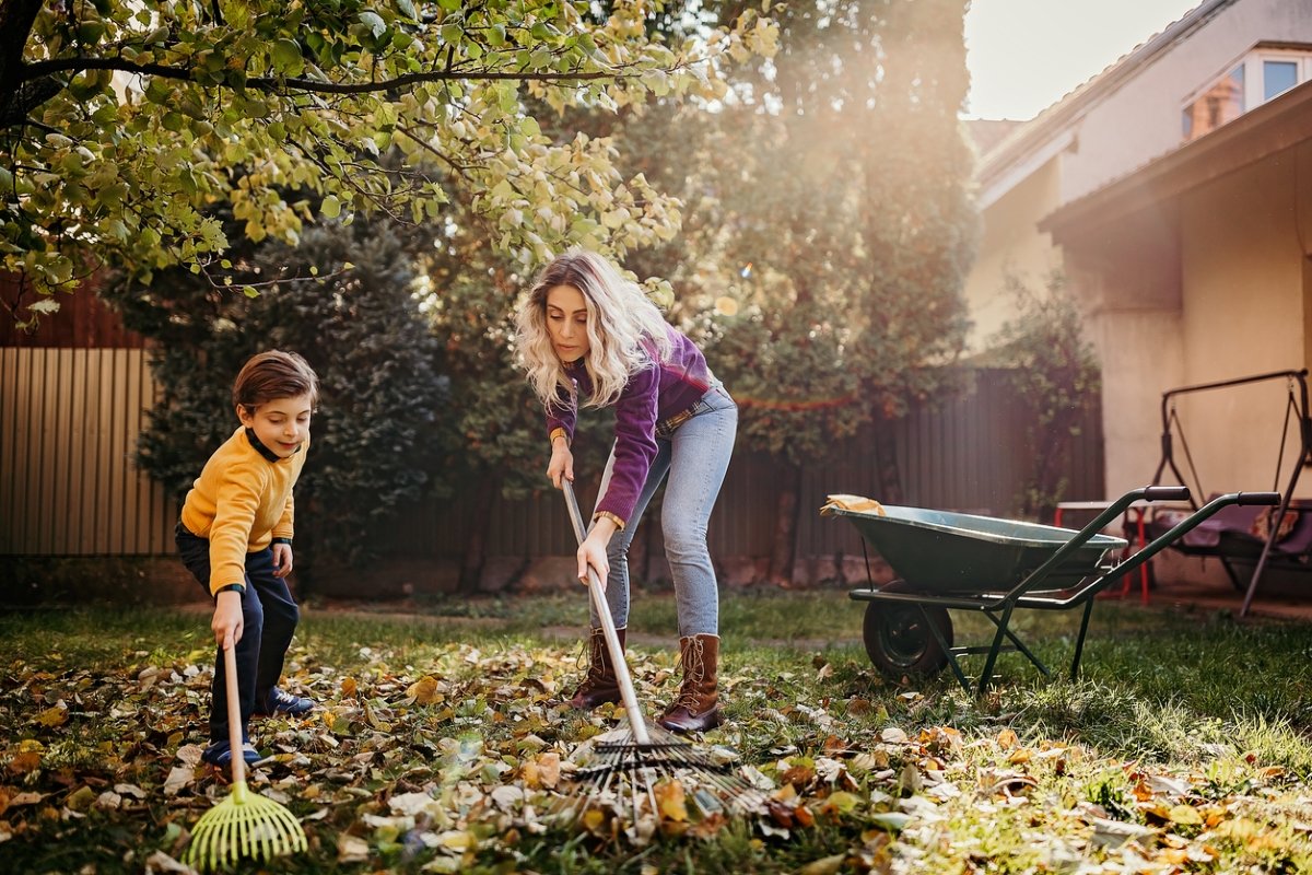 Mother and son raking leaves together.