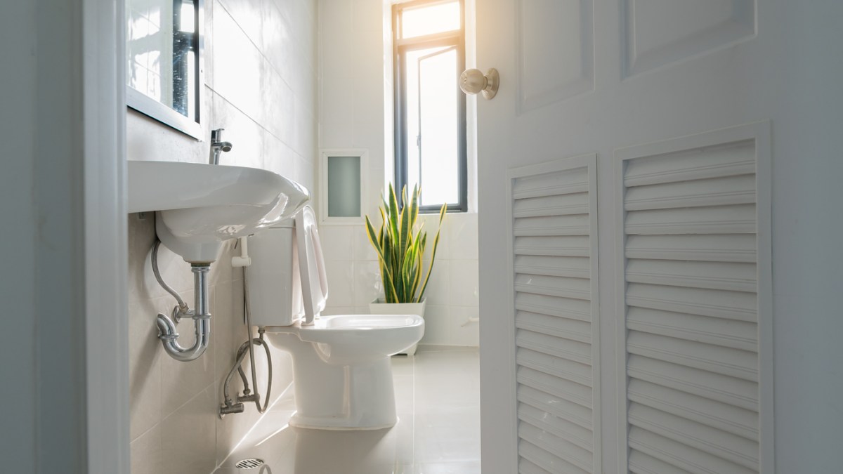 white-bathroom-seen-through-the-door-ajar-and-with-a-bright-window-in-the-background