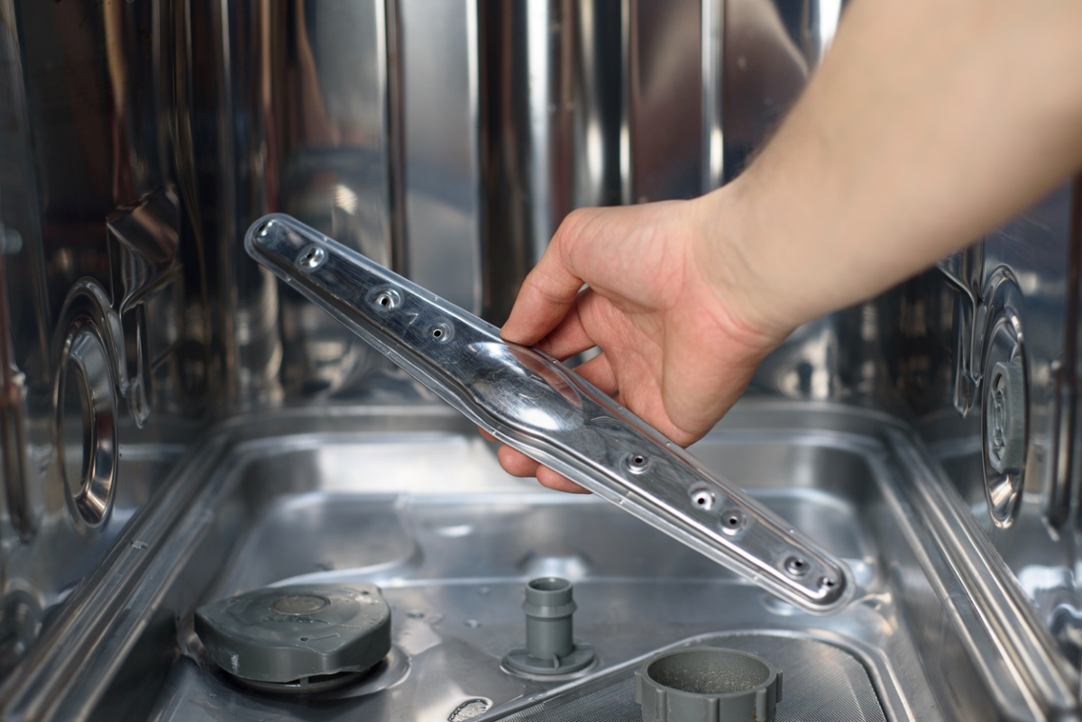 Hand holding dishwasher spray arm