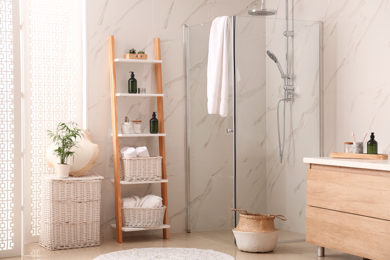 Natural elements like wood and-wicker decorate a seamless marble slab bathroom with glass shower and wood vanity.