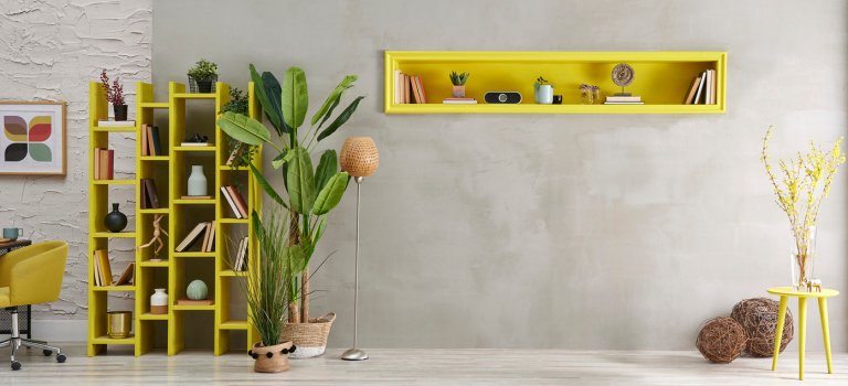 Grey stone wall, room, interior style with yellow niche, green vase of plant, bookshelf decor.