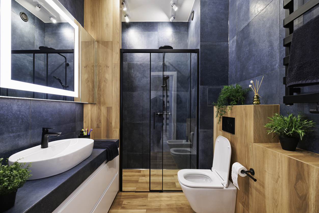 A wood and blue bathroom has smooth large blue tiles on the walls.