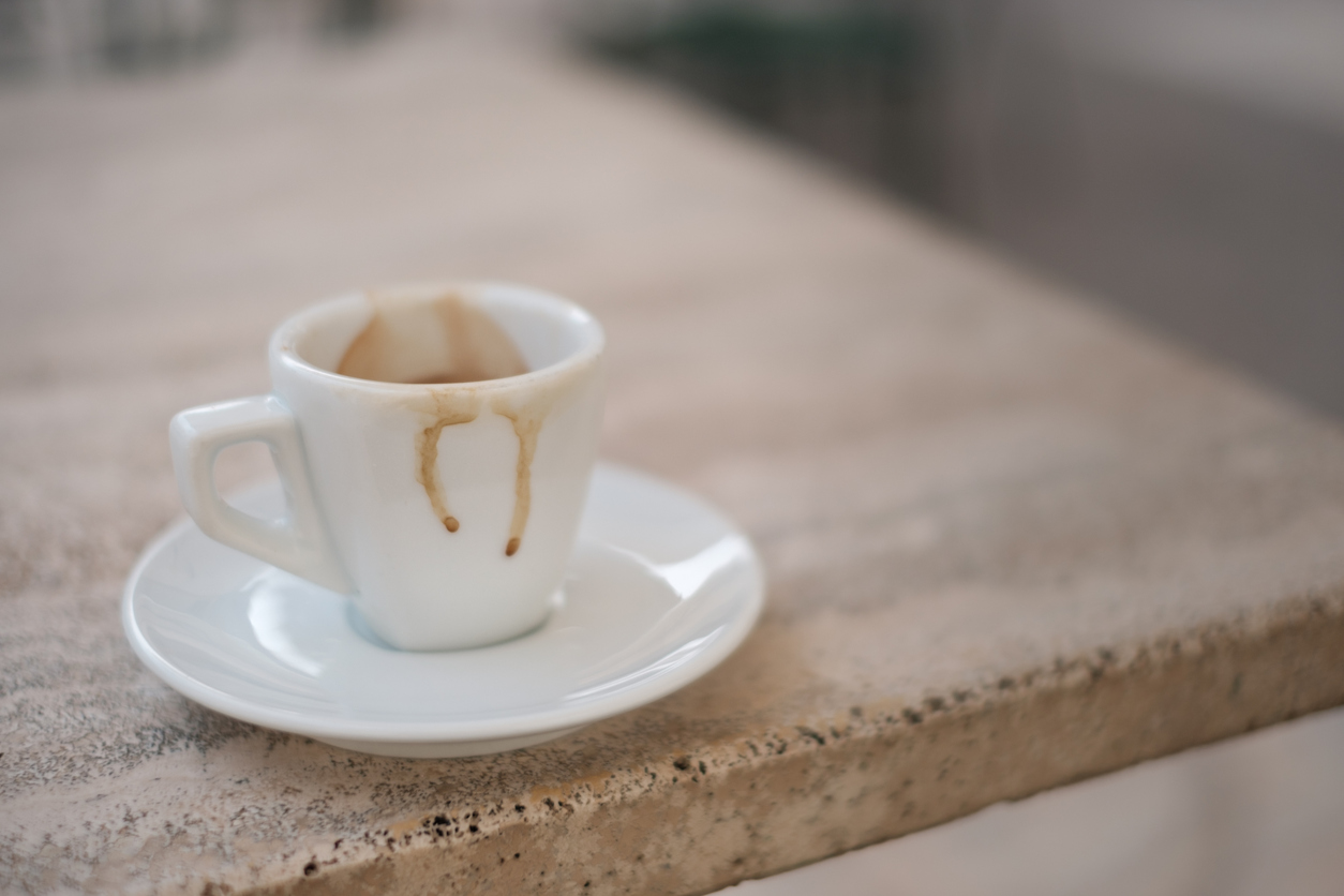 An empty dirty espresso cup on a marble table top.