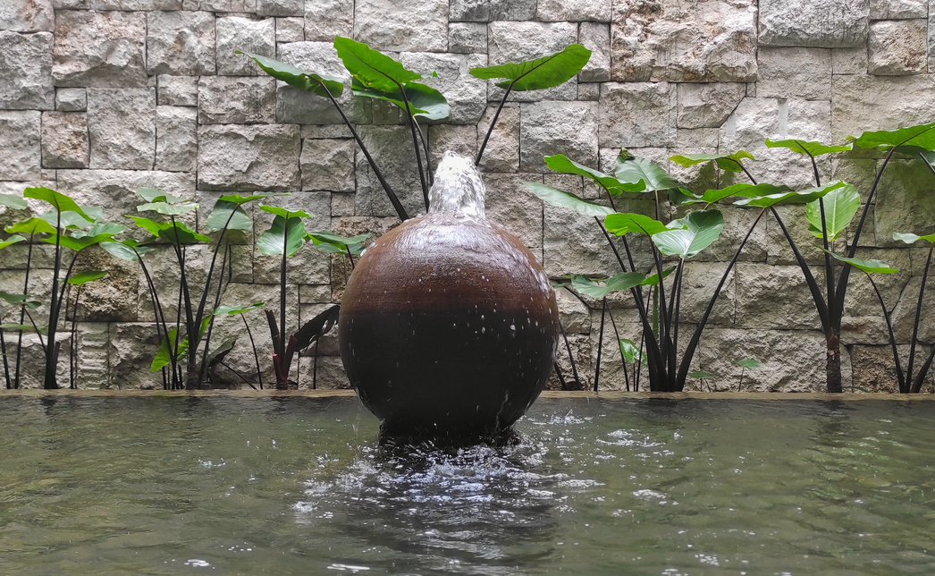 Fountain with ball shape on the pool of garden in the house during sunny day