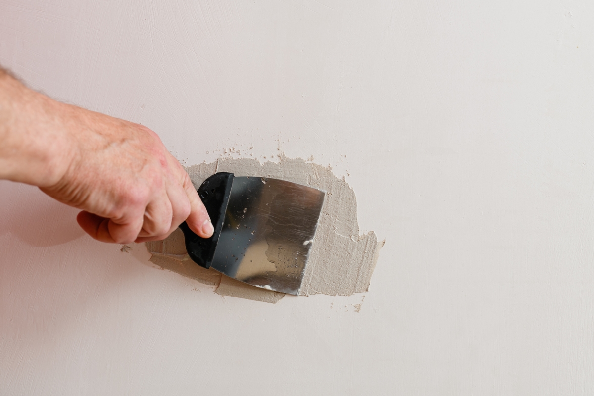 Person spackling over small hole in wall
