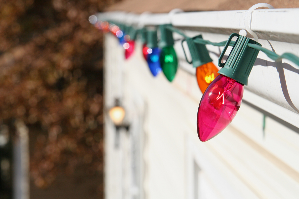 Close-up of Christmas lights on the roofline of a home, held in place with plastic clips.