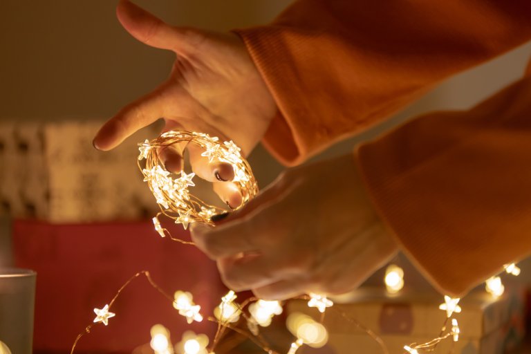 Hands-are-unwinding-a-string-of-star-shaped-lights.