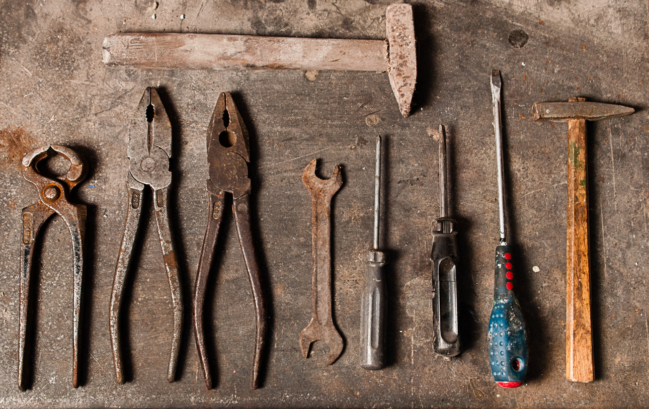 Overhead view of rusty tools on a wooden workbench.