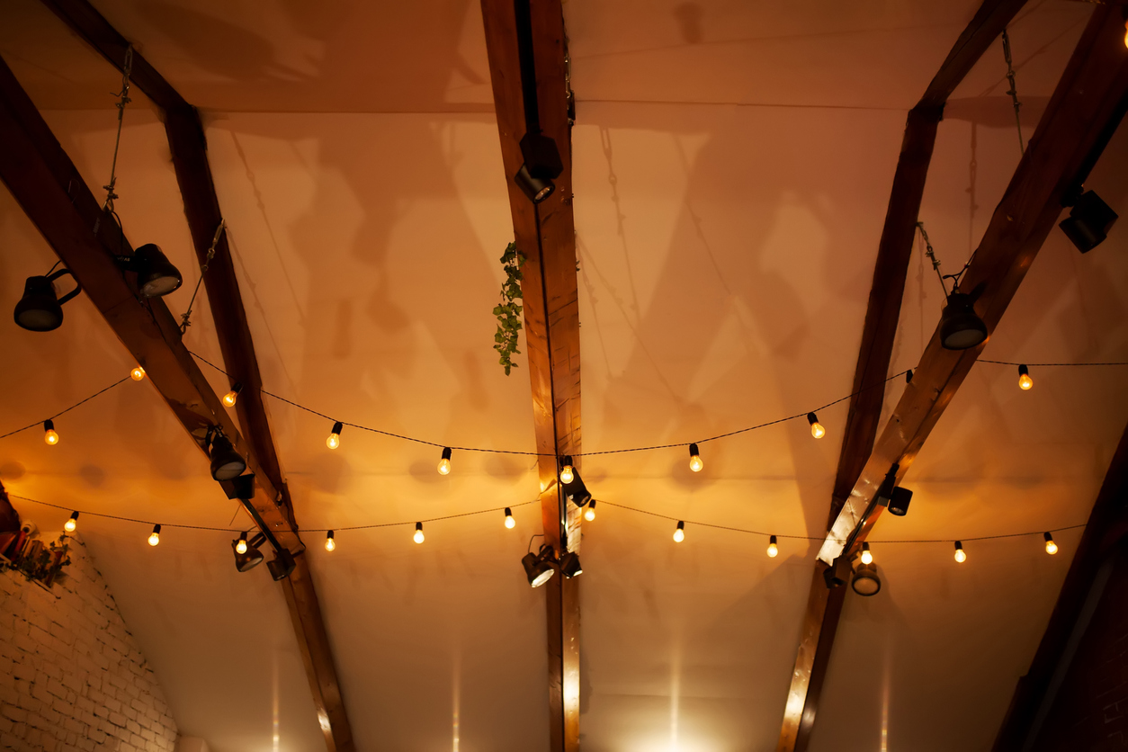 Strings-of-globe-lights-decorate-the-rafters-of-a-tall-house-ceiling.