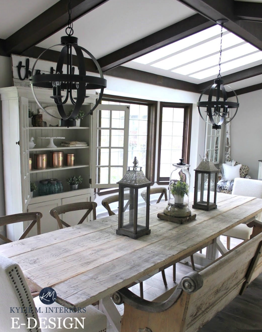 A dining room with a long antique wood table and walls painted light gray