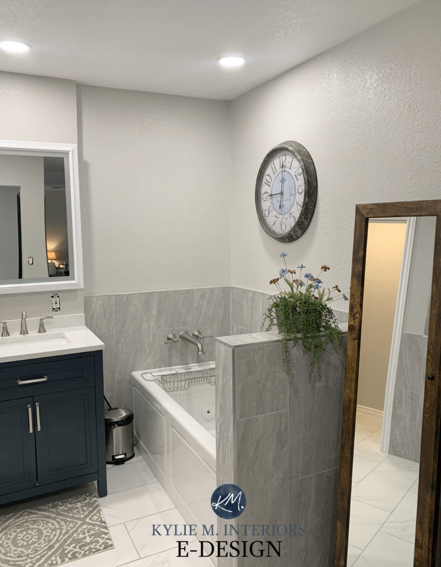 A bathroom with large dark grey tiles and a floor length mirror with grey walls