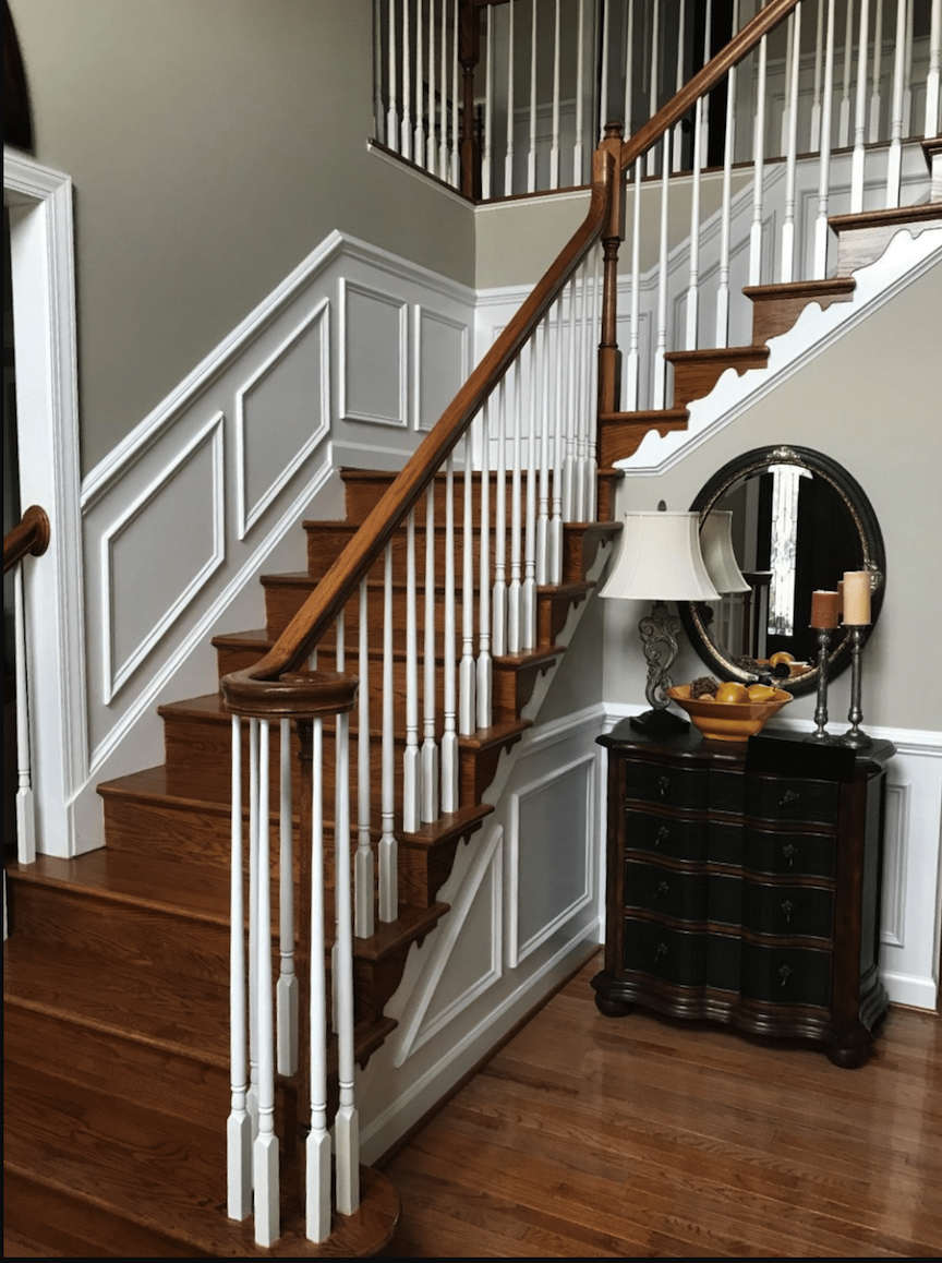 An elegant staircase in a hallway painted with grey walls and white trim