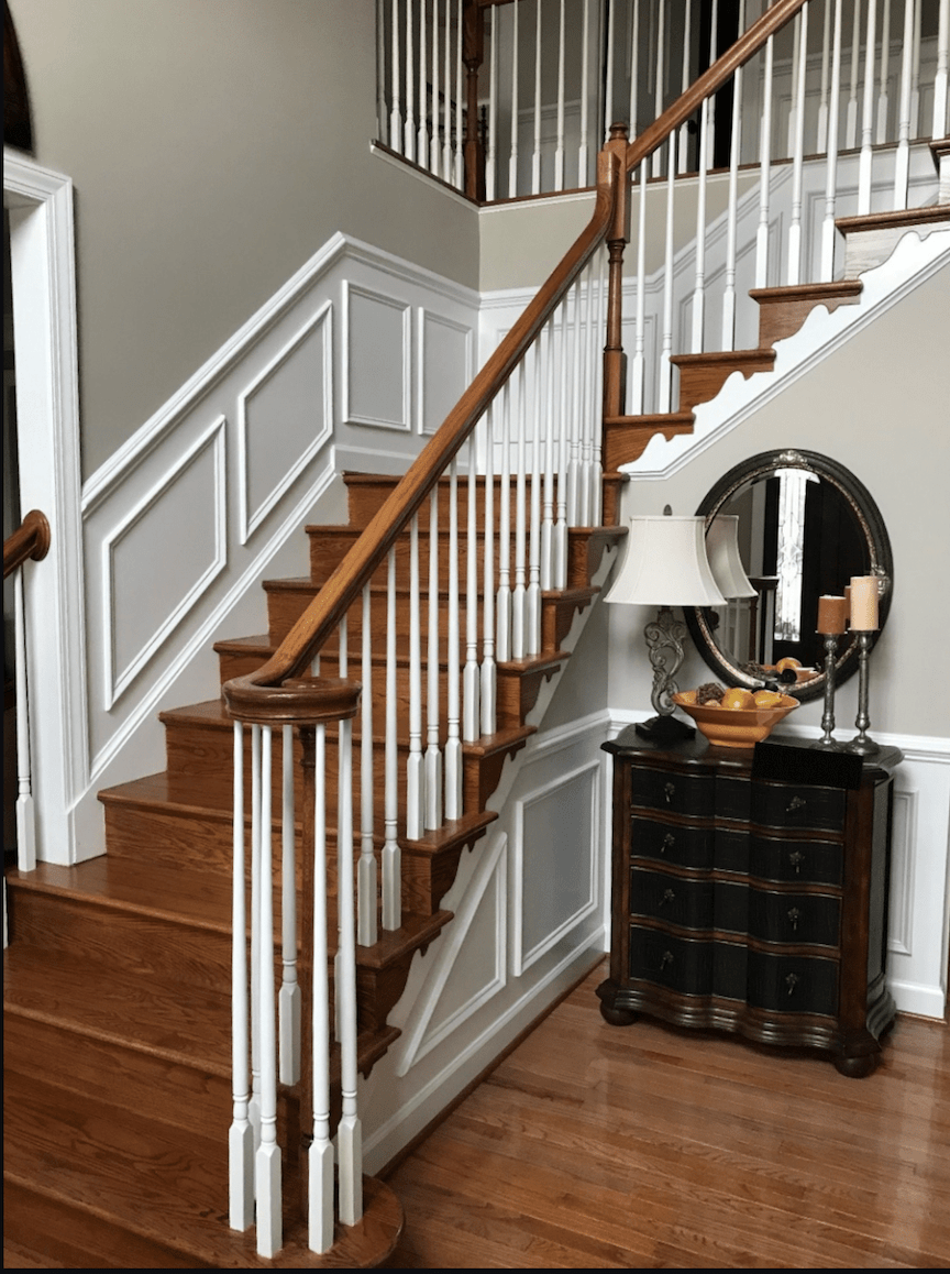 An elegant staircase in a hallway painted with grey walls and white trim