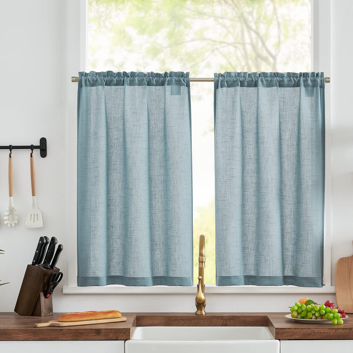 A small kitchen window with blue cafe curtains.