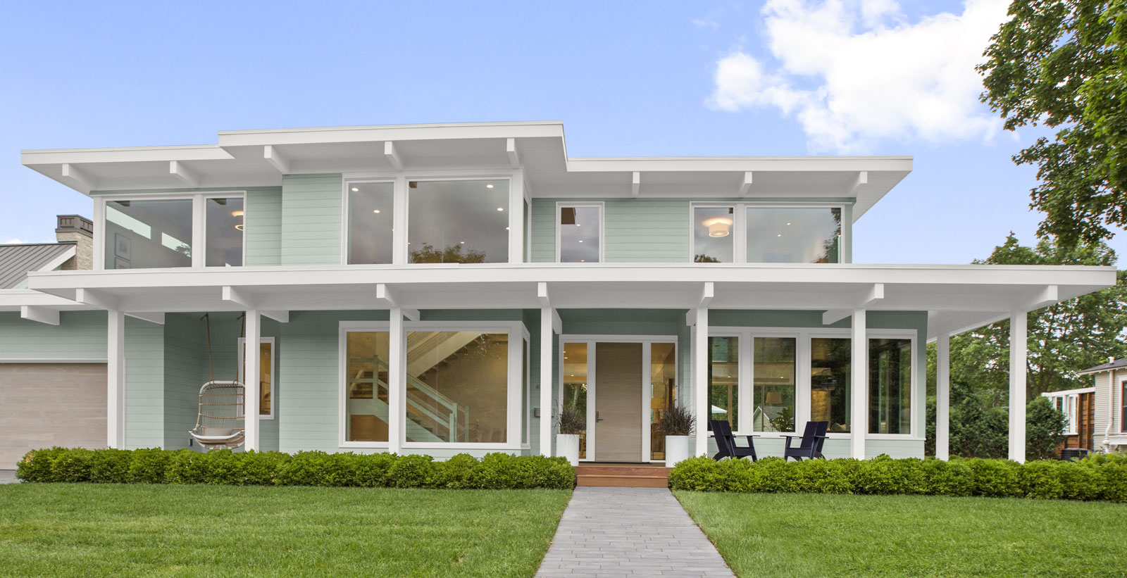 A modern house is painted in a pale blue with white trim.