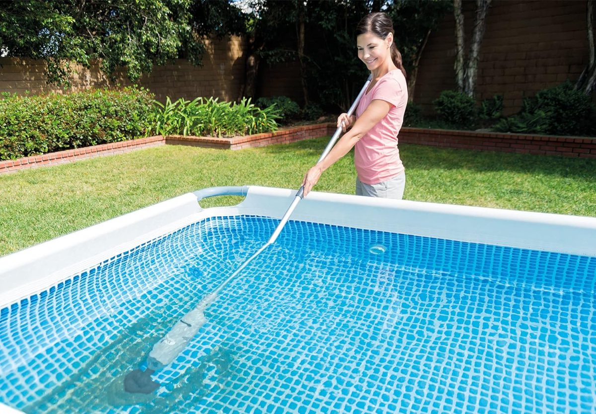 A person using the best handheld vacuum on an extender pole to remove debris from an above-ground pool.