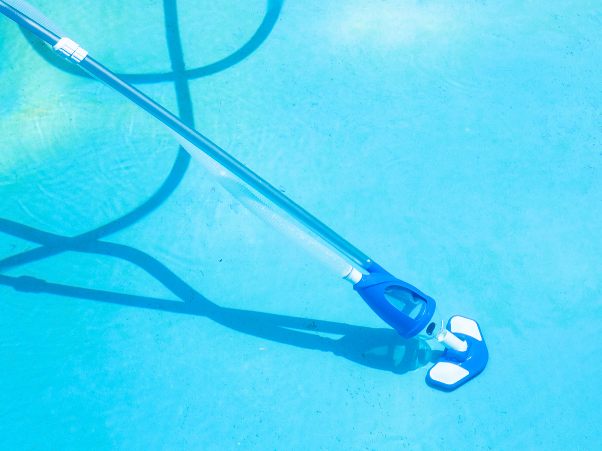 The best handheld vacuum on an extender pole with a hose attached and in use to clean the bottom of a pool.
