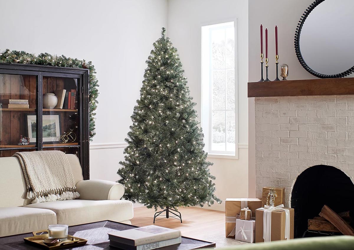 The National Tree Company Prelit North Valley Blue Spruce in a neutral-colored living room with a fireplace and presents.