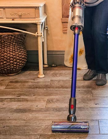 Person vacuuming wood floor with Dyson V11 Animal cordless stick vacuum