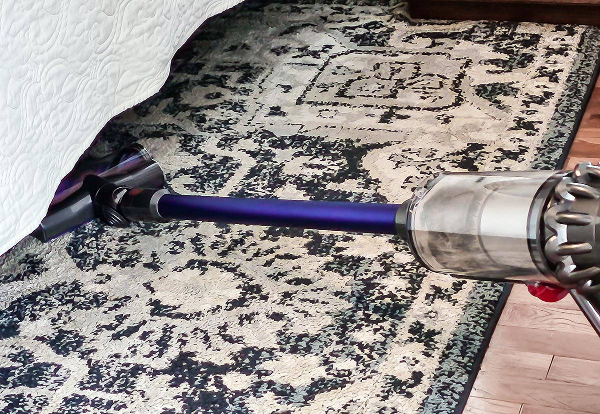 Dyson V11 Animal vacuuming black and white area rug under bed