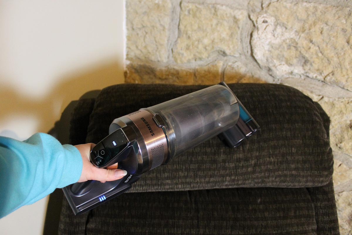 Person vacuuming an upholstered chair with Samsung Jet 75 Pet vacuum in handheld mode