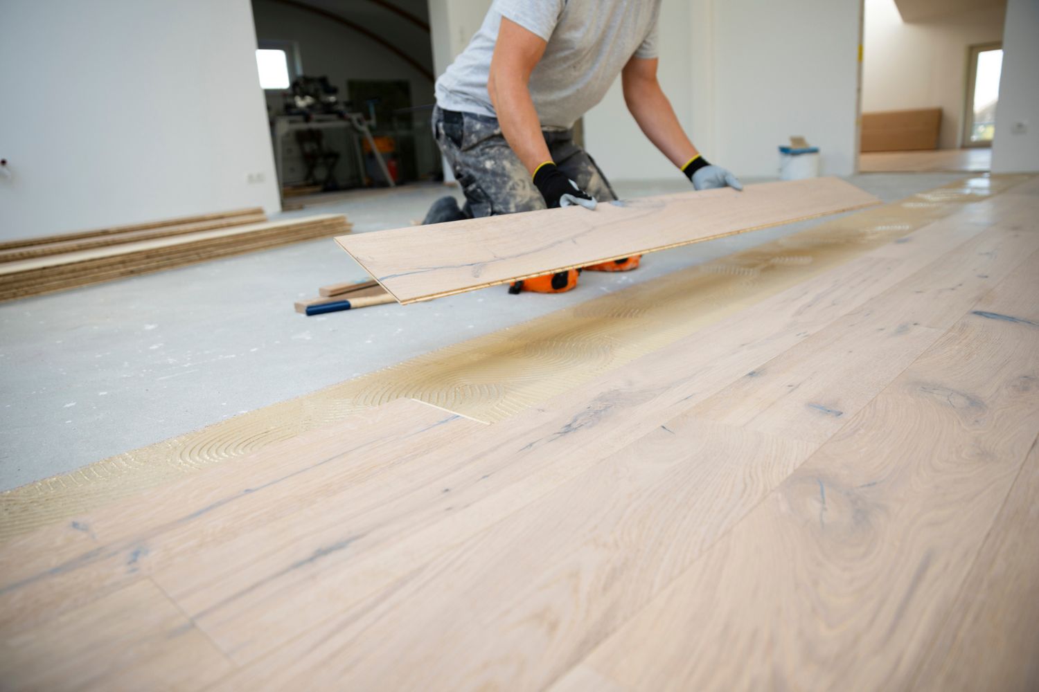 Middle-Aged Man With Grey Hair Laying Down Engineered Wood Floor, Demonstrating the Beautiful Aesthetics and Durability of the Material.