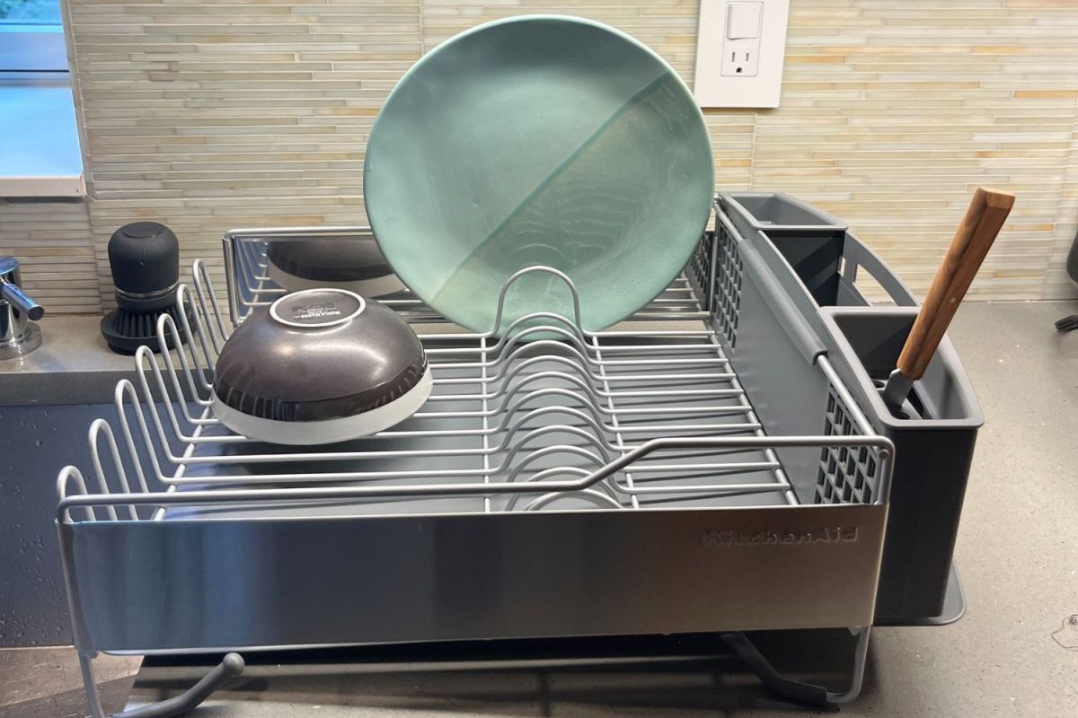The KitchenAid full-size dish-drying rack on a kitchen counter drying a blue plate and grey bowl.